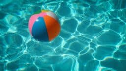 A colorful beach ball floating in a pool.