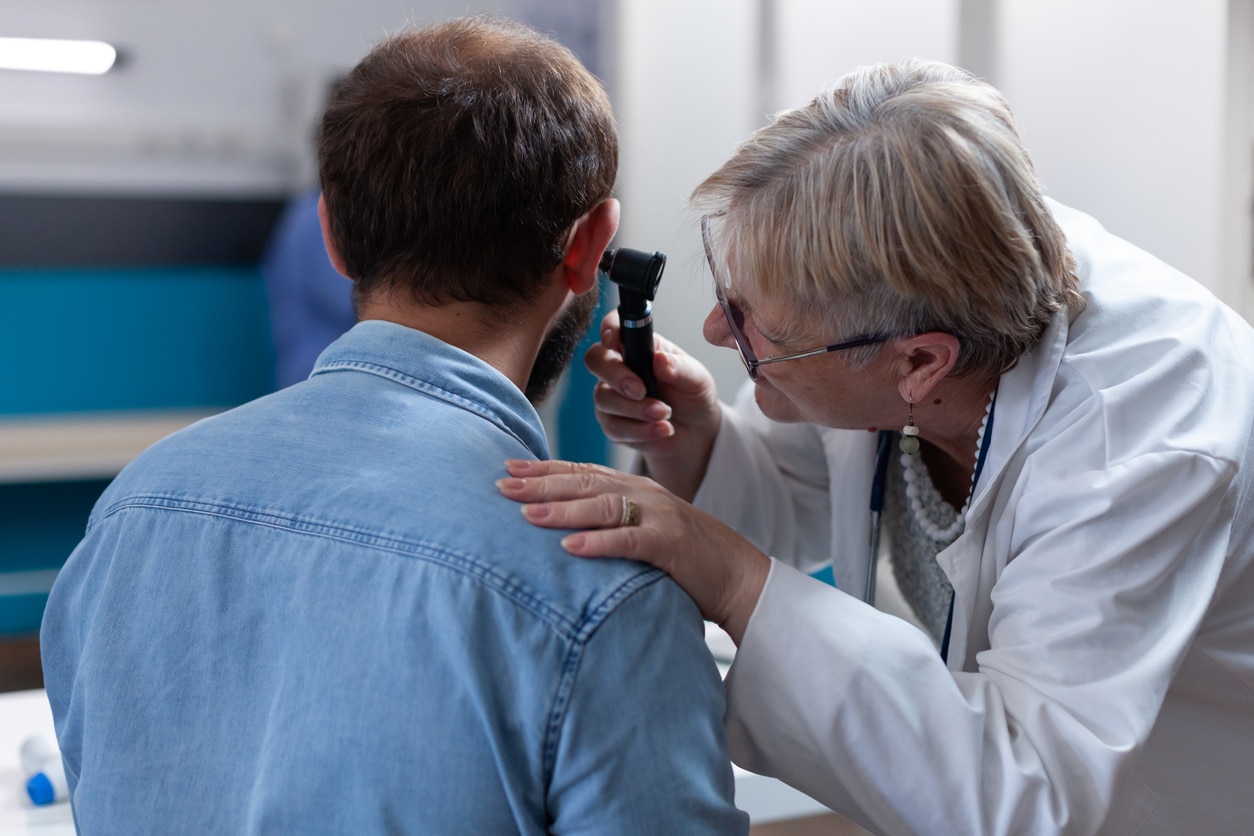 Audiologist looking inside a patient's ear.