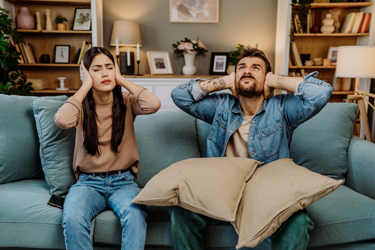 Couple on a couch covering their ears