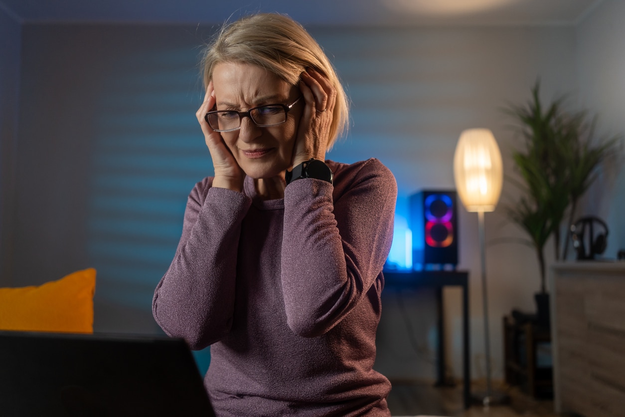Senior woman with tinnitus covering her ears