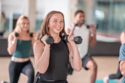 Young. woman holding dumbbells, working out in a group class.