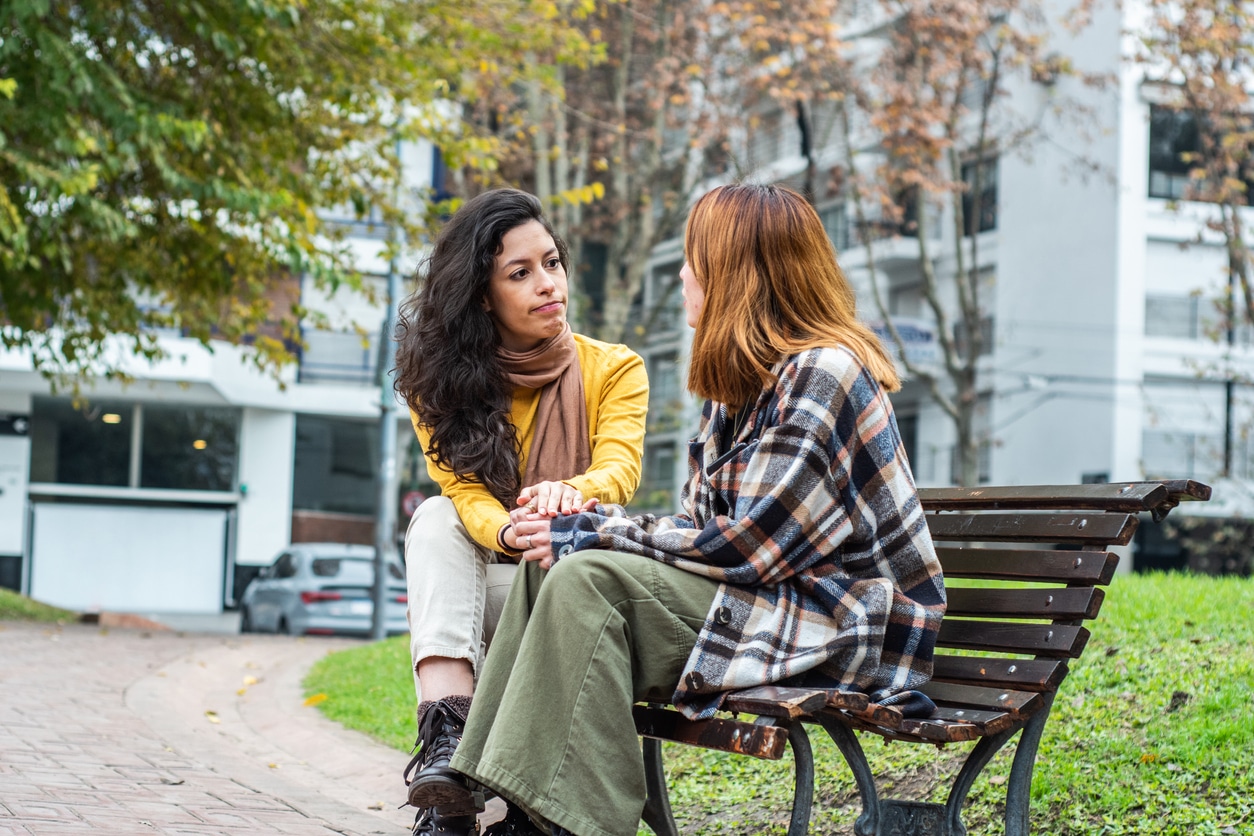 Young woman consoling her friend on the public park.