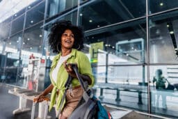 Woman using her mobile phone and looking around on a airport.
