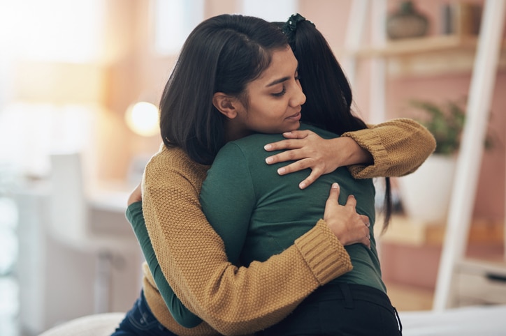Cropped shot of two young women embracing each other at home.
